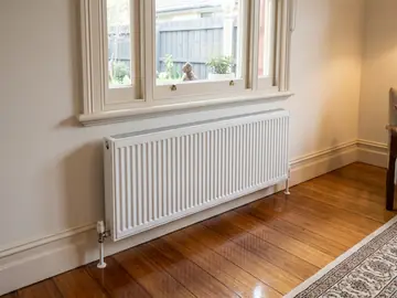White hydronic heating panel under a sash window in a period home
